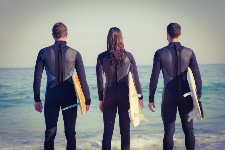 Image of 3 surfers facing ocean