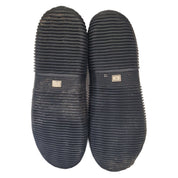 Pair of black slippers with textured sole on a white background